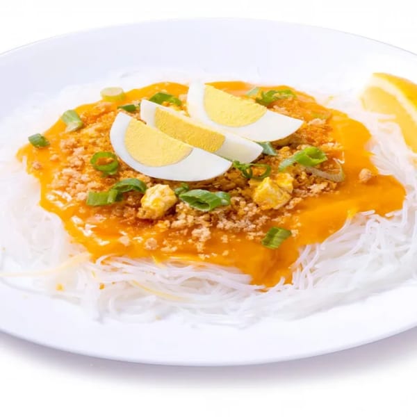 Pancit Palabok from Goldilocks, with orange sauce, crushed chicharon, sliced eggs, and green onions.